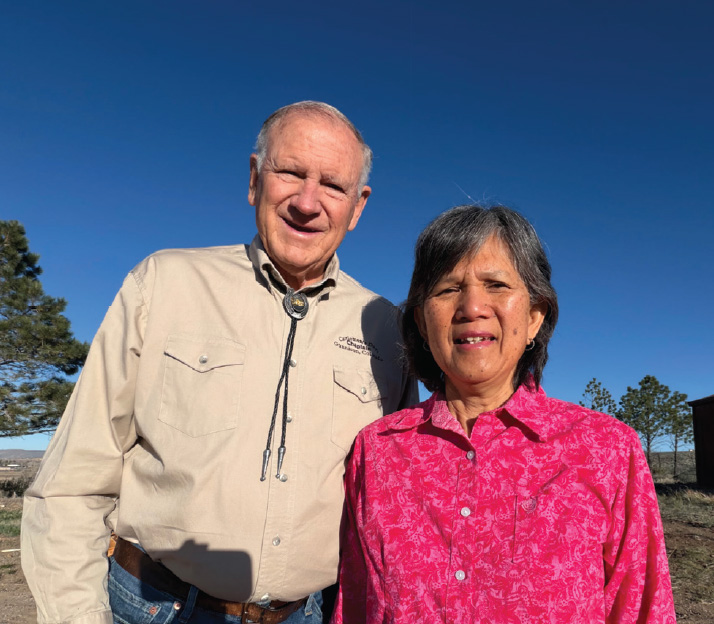 Rick Barton and his wife standing together with bright blue skies above.